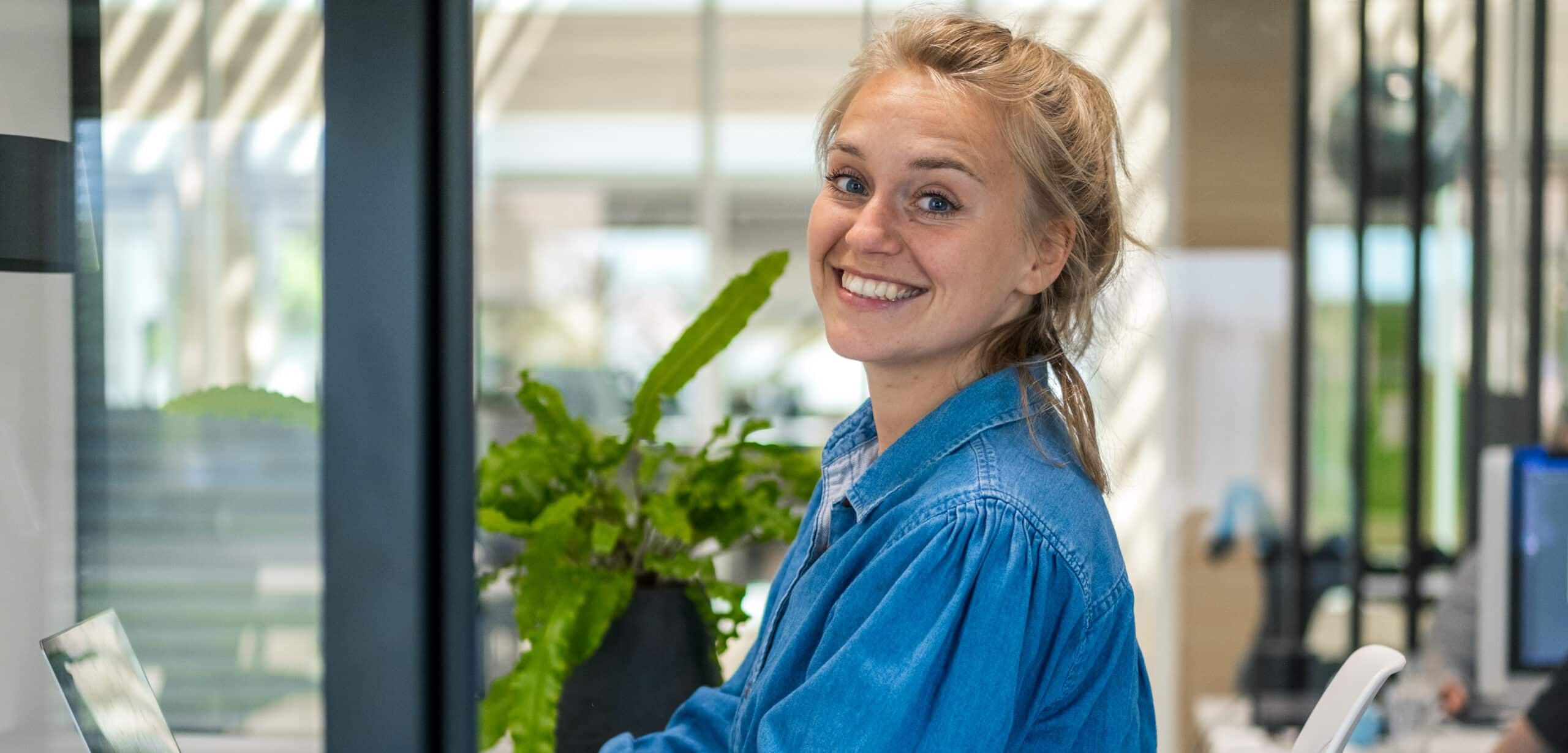 Lachende jonge vrouw zittend aan een bureau in een modern kantoor